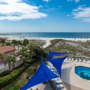 Gaze at the inviting pool area and beach access, framed by vibrant blue canopies and lush greenery