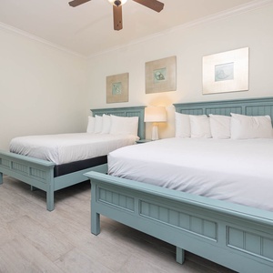 This guest bedroom features two light blue queen beds, soft white linens, and stylish decor for a relaxing retreat