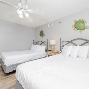 Relax in the cozy guest bedroom featuring two double beds, playful turtle decor, and a ceiling fan