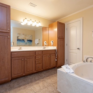 The master bath features a relaxing jetted tub, dual sinks, and warm wood cabinetry for a tranquil retreat