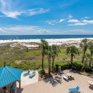 Relax under the sun in the pool area with lounge chairs and views of the beach and gentle waves in the distance