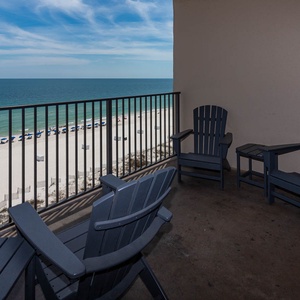 Relax in comfortable chairs on the balcony while enjoying views of the beach and gentle waves below