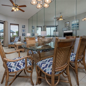 Enjoy meals at the glass dining table surrounded by comfortable rattan chairs, with a view of the beachfront patio