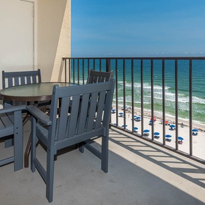 Experience stunning views from the balcony, featuring a table and chairs perfect for relaxing by the beach