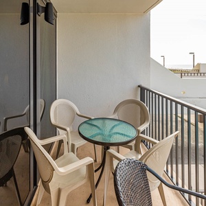This balcony features a round glass table and four chairs, perfect for enjoying beachfront views and relaxing moments