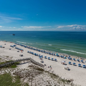 Breathtaking view of a serene beach lined with colorful umbrellas under a clear blue sky, perfect for a relaxing getaway