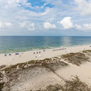This living area features a stunning beachfront view with inviting blue umbrellas lining the sandy shore