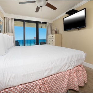 The master bedroom features a king bed, a wall-mounted TV, and a breathtaking view from the balcony