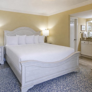 Master bedroom featuring a king bed with white linens, nightstands, and an adjoining bathroom area