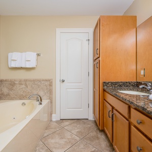 The master bath features a relaxing jetted tub, elegant granite countertops, and warm wood cabinetry for a serene retreat