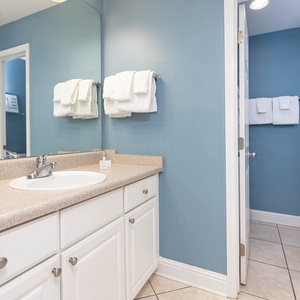 The guest bathroom features a spacious countertop, bright blue walls, and fresh towels for a refreshing stay