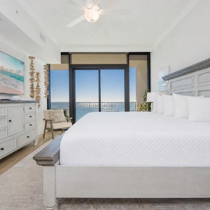 Serene master bedroom featuring a king bed, stylish decor, and expansive windows with stunning beach views
