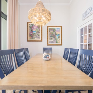 Spacious dining area with a large wooden table, navy chairs, and vibrant artwork, perfect for family meals and gatherings