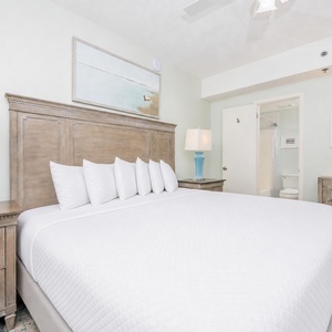 Inviting room featuring a plush king bed, stylish blue lamp, and adjoining bathroom