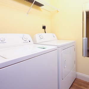 The laundry room features a washer and dryer set against a bright yellow wall, ensuring convenience during your stay