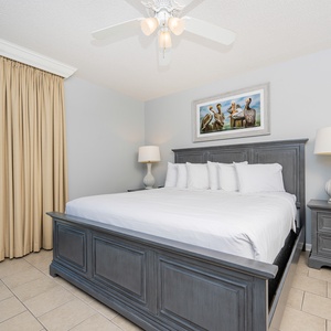 Unwind in this spacious master bedroom featuring a king bed, lamp, and a view of the balcony with beachfront views