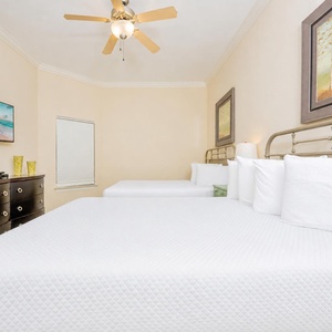 Cozy guest bedroom featuring two comfortable queen beds, a flat-screen TV, and tasteful artwork on the walls