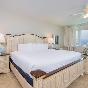Master bedroom featuring a king bed, elegant decor, and large windows offering a serene view of the surroundings