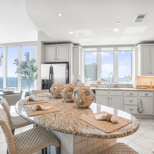 This bright kitchen features granite countertops, stainless appliances, and a stunning beach view from the dining area