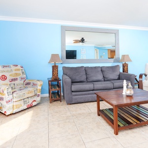 Bright blue walls complement a cozy seating area with a gray sofa and colorful accent chair, perfect for relaxation