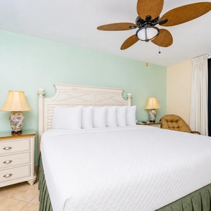 Inviting master bedroom featuring a king-sized bed, coastal decor, and a balcony with a breathtaking view