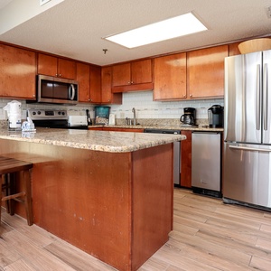The kitchen features rich wood cabinetry, granite countertops, stainless appliances, a Keurig and a coffee maker 
