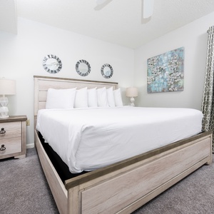 The cozy bedroom features a large king bed, a stylish nightstand, and decorative wall art for a serene vibe