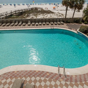 Enjoy the inviting pool area with a sparkling blue water view and comfortable lounge chairs just steps from the beach