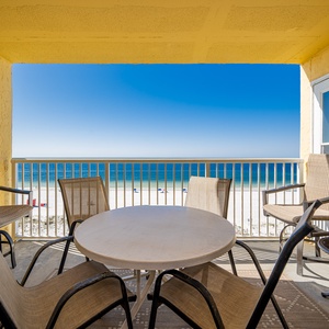 Enjoy stunning beachfront views from this cozy balcony, featuring a round table and comfortable seating for relaxation