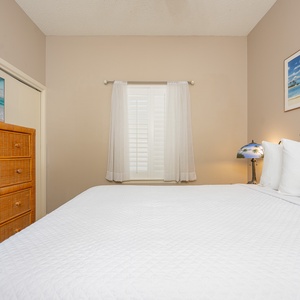 Rest in this comfortable guest bedroom featuring a queen bed, dresser, and natural light from the window