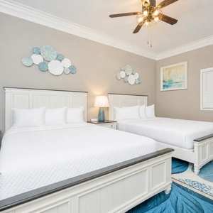 Cheerful guest bedroom featuring two queen beds, coastal decor, and stylish accents