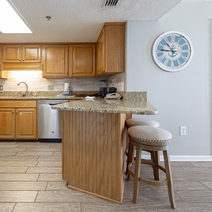 Bright wood cabinetry complements the granite countertops in this fully-equipped kitchen with a convenient breakfast bar
