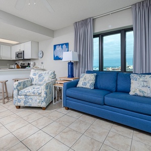 Relax on the comfortable blue sofa with queen sleeper while enjoying panoramic views through large windows