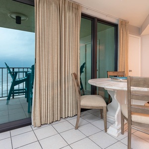 This dining area features a round table, comfortable chairs, and a beautiful view from the balcony, perfect for relaxation