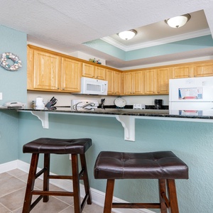 Inviting kitchen with warm wood cabinets, sleek granite countertops, and cozy bar seating for a perfect getaway