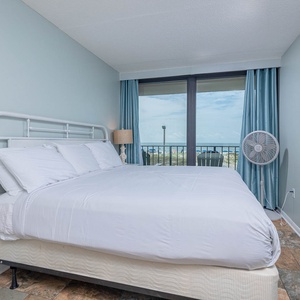 The master bedroom features a comfortable bed and offers a stunning beachfront view through large sliding glass doors