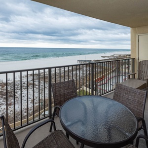 Enjoy a relaxing moment on the balcony with a round table and chairs, overlooking the tranquil beachfront and white sand