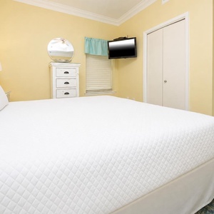 The master suite features a plush king bed, while a TV and dresser enhance the inviting guest room atmosphere