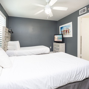 Unwind in the comfortable guest bedroom featuring two twin beds with soft bedding, stylish decor, and a TV