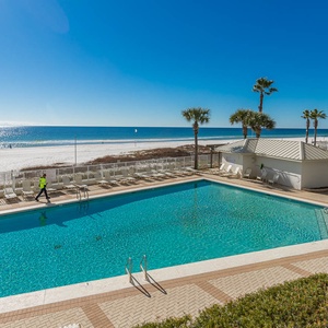 The pool area features a stunning beachfront view, with lounge chairs lining the sparkling water for a relaxing retreat
