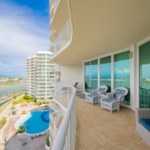 View from the balcony with stylish seating, overlooking the sparkling pool and tranquil waterways