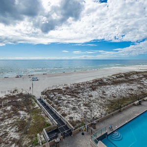 Gaze at the tranquil waters and beach from your spacious outdoor balcony overlooking the pool area, perfect for relaxation