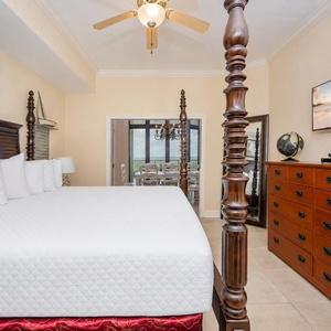 Elegant master bedroom featuring a four-poster bed, flat-screen TV, and a view of the dining area