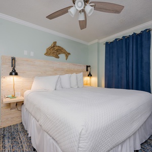 Relaxing master bedroom featuring a cozy king bed with white linens and charming coastal decor, perfect for relaxation