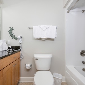 Stylish guest bathroom featuring a sleek countertop, ample towels, and a relaxing tub-shower for your comfort