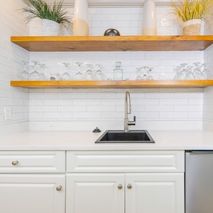 Grab a chilled drink or create a cocktail at this sleek wet bar with an elegant glassware display
