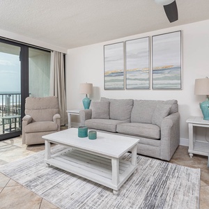 This inviting living area features a comfortable gray sofa, a lovely view of the beach, and a TV for entertainment