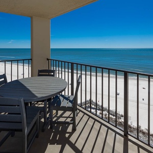 Enjoy stunning views from the balcony, featuring a round table and chairs overlooking the pristine serene beach