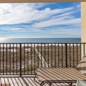 Lounge chairs on the balcony offer a serene view of the tranquil gulf and white sand, perfect for relaxation and unwinding
