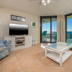 Cozy living area features a TV, colorful seating, and large windows showcasing a stunning beachfront view